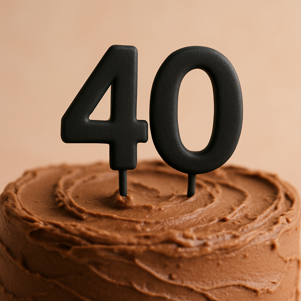 A matte black number 40 cake topper standing in chocolate frosting on a cake.